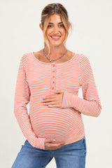 woman wearing a pink and white striped maternity long sleeve top and holding her baby bump