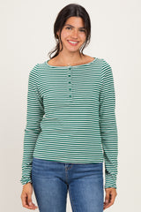 woman wearing a green and white striped long sleeve henley top with buttons and blue jeans