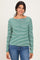 woman wearing a green and white striped long sleeve henley top with buttons and blue jeans