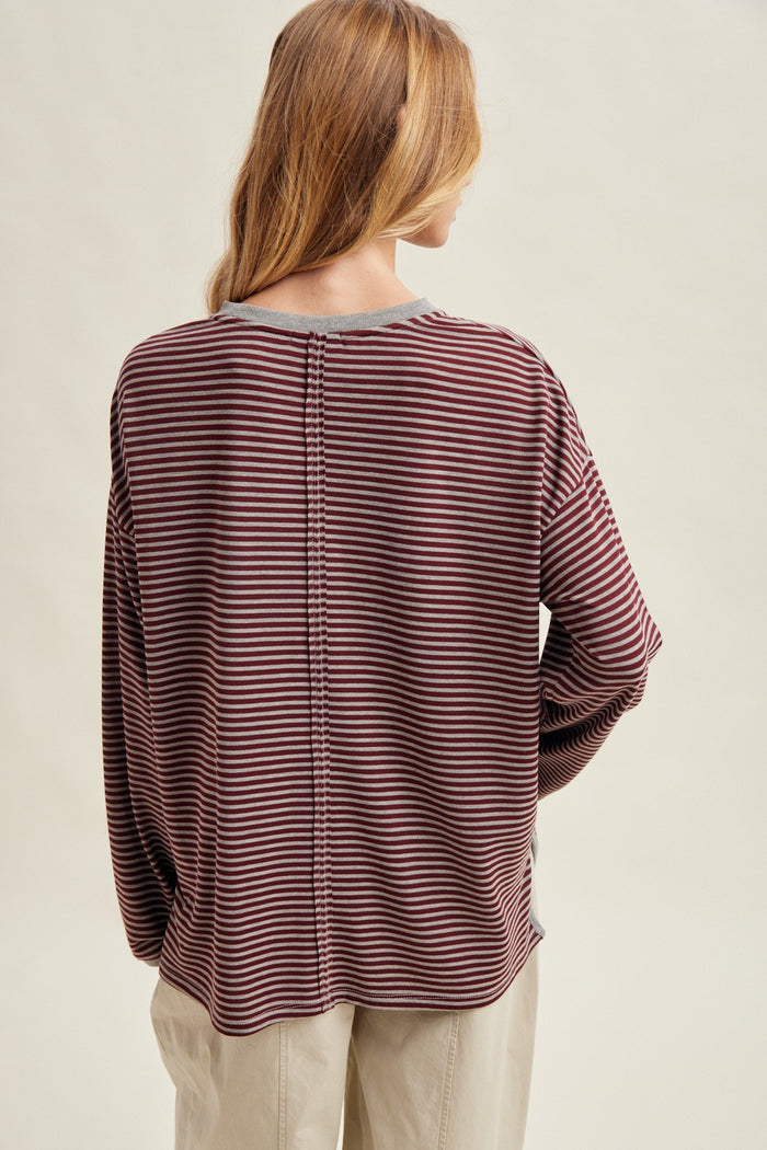 woman wearing a maroon and gray striped long sleeve top showing a relaxed fit and back seam detail