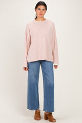 woman wearing a light pink and white striped oversized long sleeve top with blue wide leg jeans and brown heeled mules