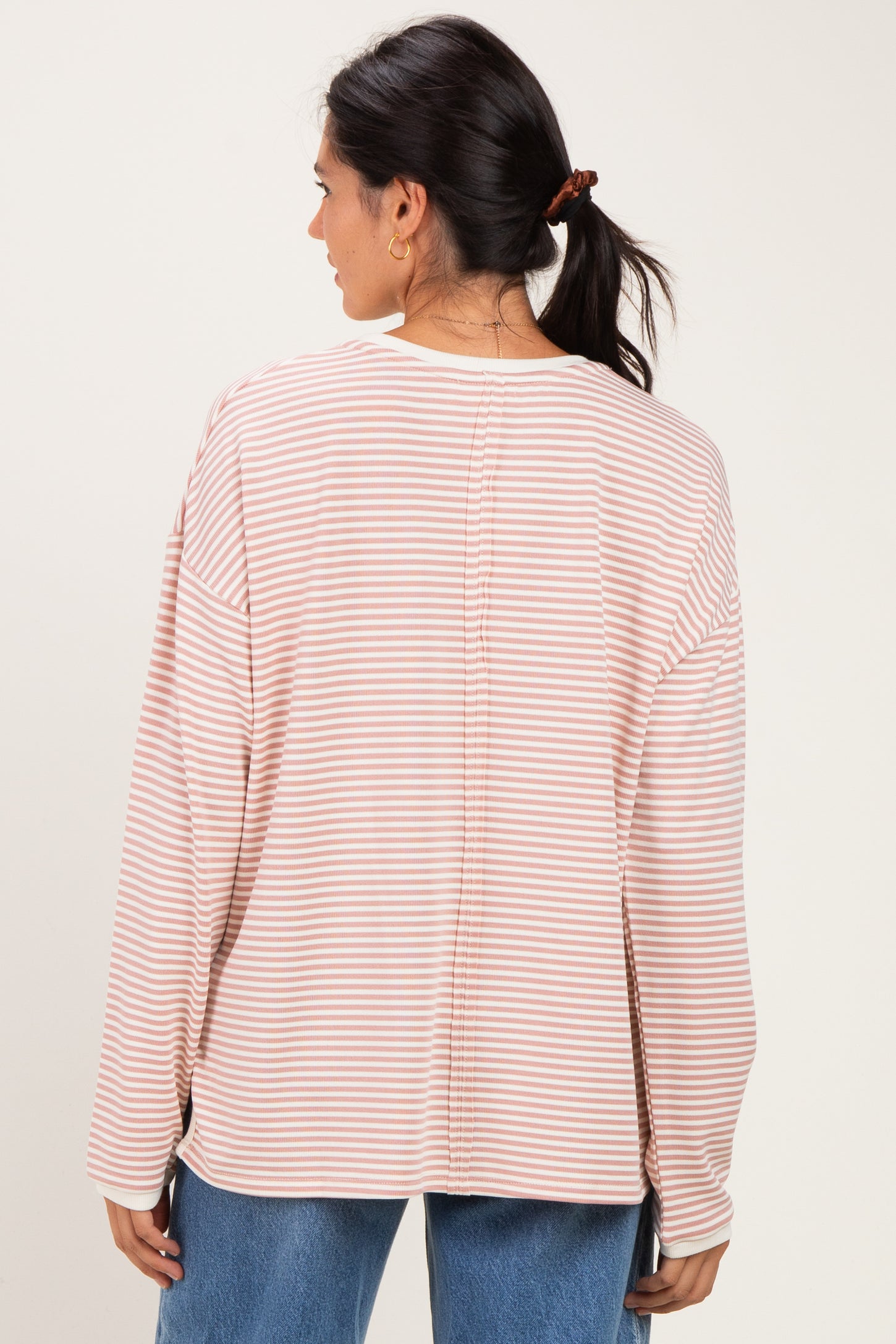 woman wearing a pink and white striped long sleeve top, view from the back with relaxed fit and dropped shoulders