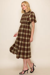 woman wearing a brown and green plaid midi dress with short sleeves and a fitted waistband