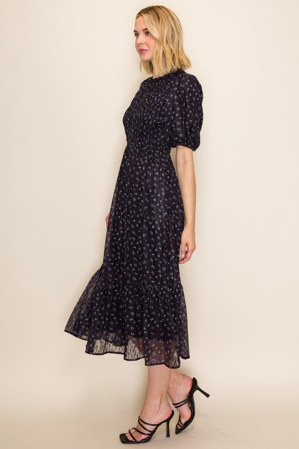 woman wearing a navy blue midi dress with floral print and puff sleeves, styled with strappy heels