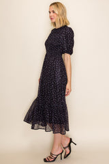 woman wearing a navy blue midi dress with floral print and puff sleeves, styled with strappy heels
