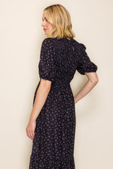woman wearing a black floral maxi dress with puff sleeves and a smocked bodice, shown from the side
