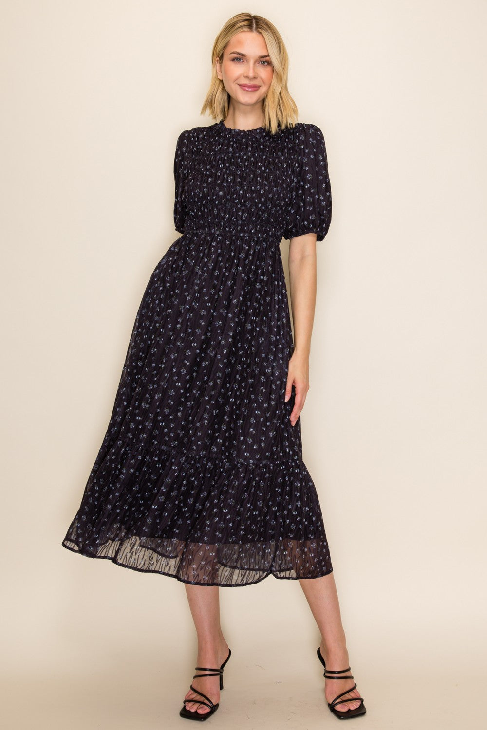 woman wearing a dark floral midi dress with puff sleeves and a smocked bodice