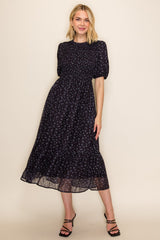 woman wearing a dark floral midi dress with puff sleeves and a smocked bodice