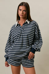 woman wearing a navy and gray striped oversized polo top with a contrasting white collar and matching shorts