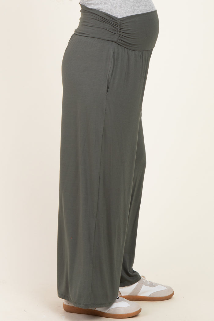 woman wearing a pair of dark green maternity wide-leg pants with a gathered waistband and visible baby bump