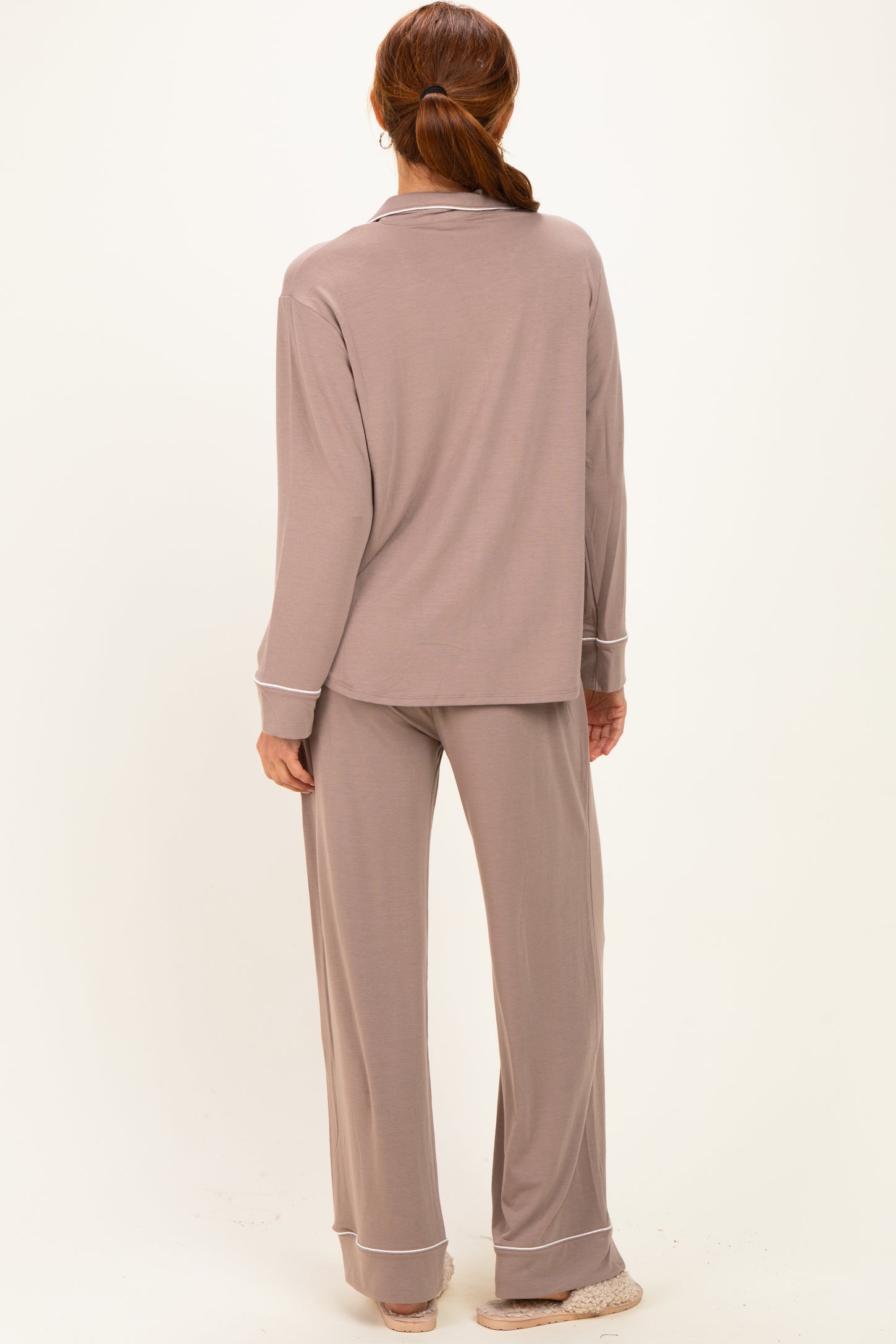 woman wearing a taupe long sleeve pajama set with matching pants and white trim details