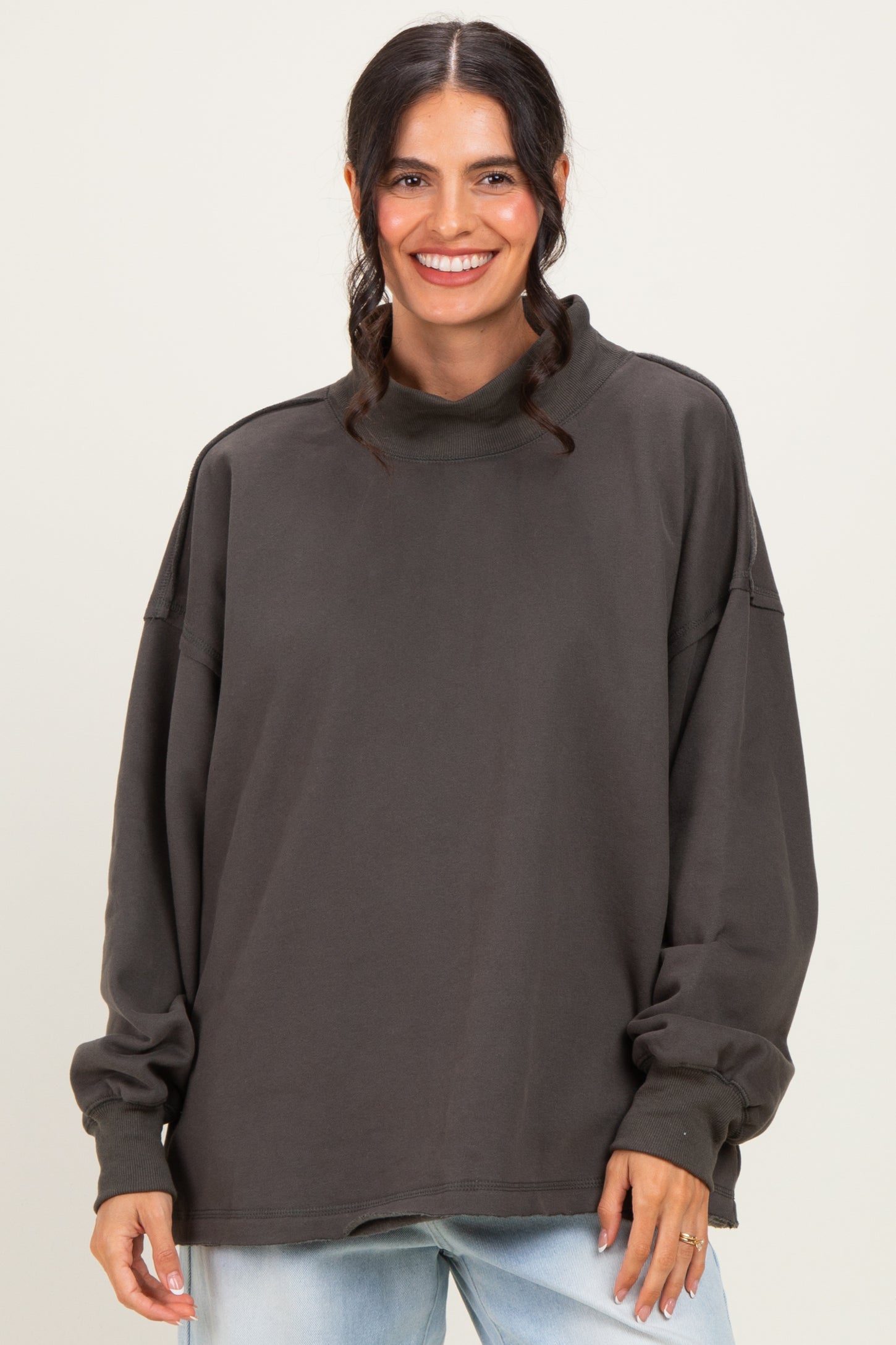 woman wearing a loose-fitting charcoal gray long sleeve mock neck sweatshirt with dropped shoulders