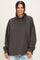 woman wearing a loose-fitting charcoal gray long sleeve mock neck sweatshirt with dropped shoulders