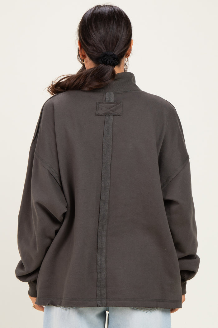 woman wearing an oversized dark gray pullover sweatshirt with a high collar and back seam detail