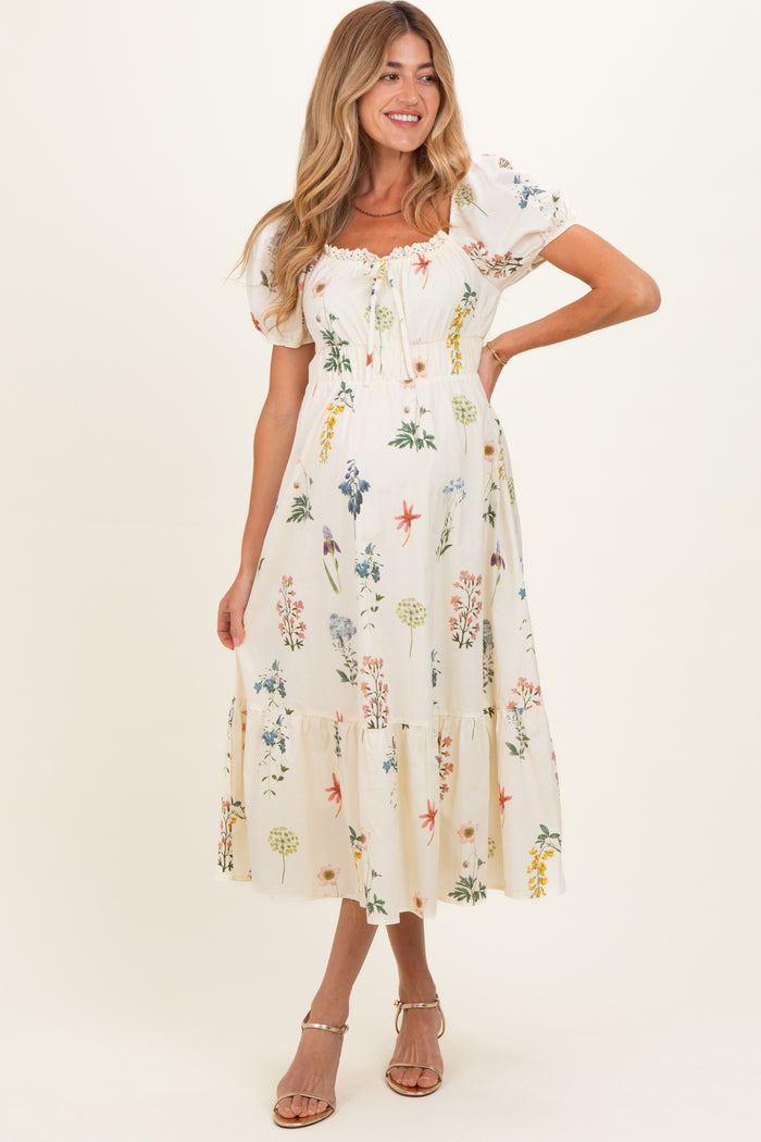woman wearing a floral print maternity maxi dress with short puff sleeves and a tiered hemline