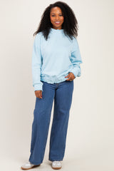 woman wearing a light blue oversized sweatshirt with a gathered hem and paired with wide-leg jeans