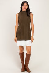 woman wearing an olive green ribbed knit sleeveless dress with a white pleated skirt and knee-high brown boots