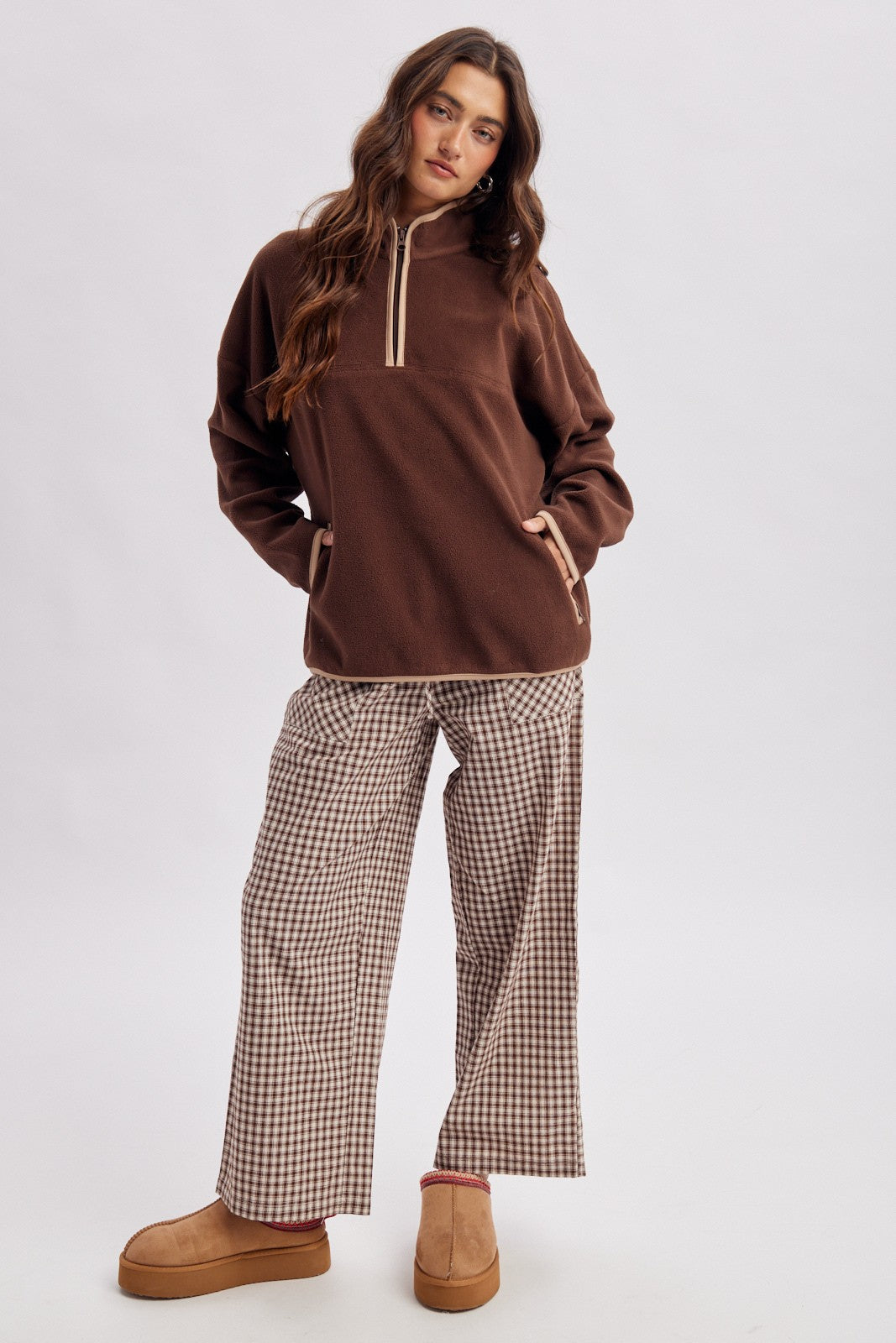 woman wearing a brown fleece pullover with a half zip and plaid wide-leg pants