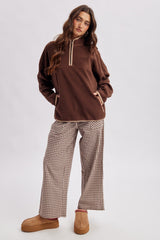 woman wearing a brown fleece pullover with a half zip and plaid wide-leg pants