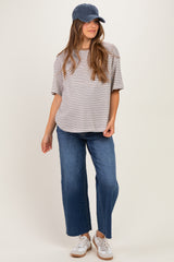 woman wearing a gray and white striped maternity t-shirt with blue wide-leg jeans and a baseball cap