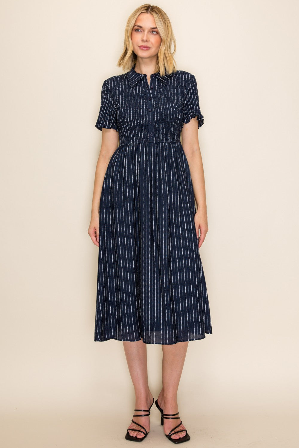 woman wearing a navy blue striped midi dress with a smocked waist and short sleeves