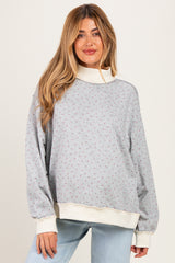 woman wearing a gray maternity sweatshirt with floral print and cream accents, styled with relaxed fit and long sleeves