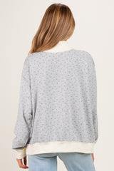 woman wearing a gray floral maternity sweatshirt with a relaxed fit and cream-colored cuffs