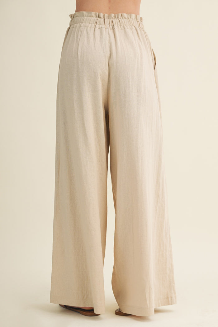 woman wearing light beige wide leg pants with an elastic waistband, viewed from the back
