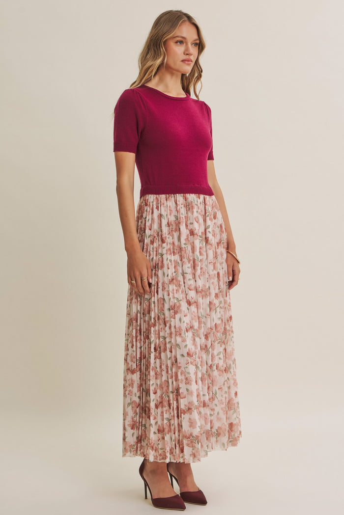woman wearing a fuchsia short sleeve top and a floral pleated maxi skirt with heeled shoes
