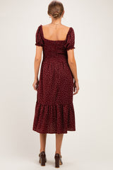 woman wearing a burgundy maternity dress with puff sleeves and white polka dots, featuring a ruffled hem and smocked back