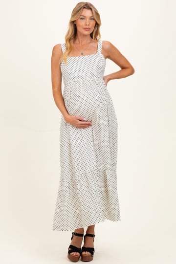 woman wearing a white polka dot maternity maxi dress and holding her baby bump