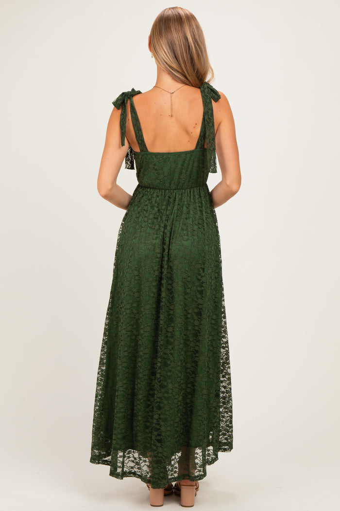woman wearing a dark green maxi dress with tie straps and semi-sheer lace overlay, shown from the back