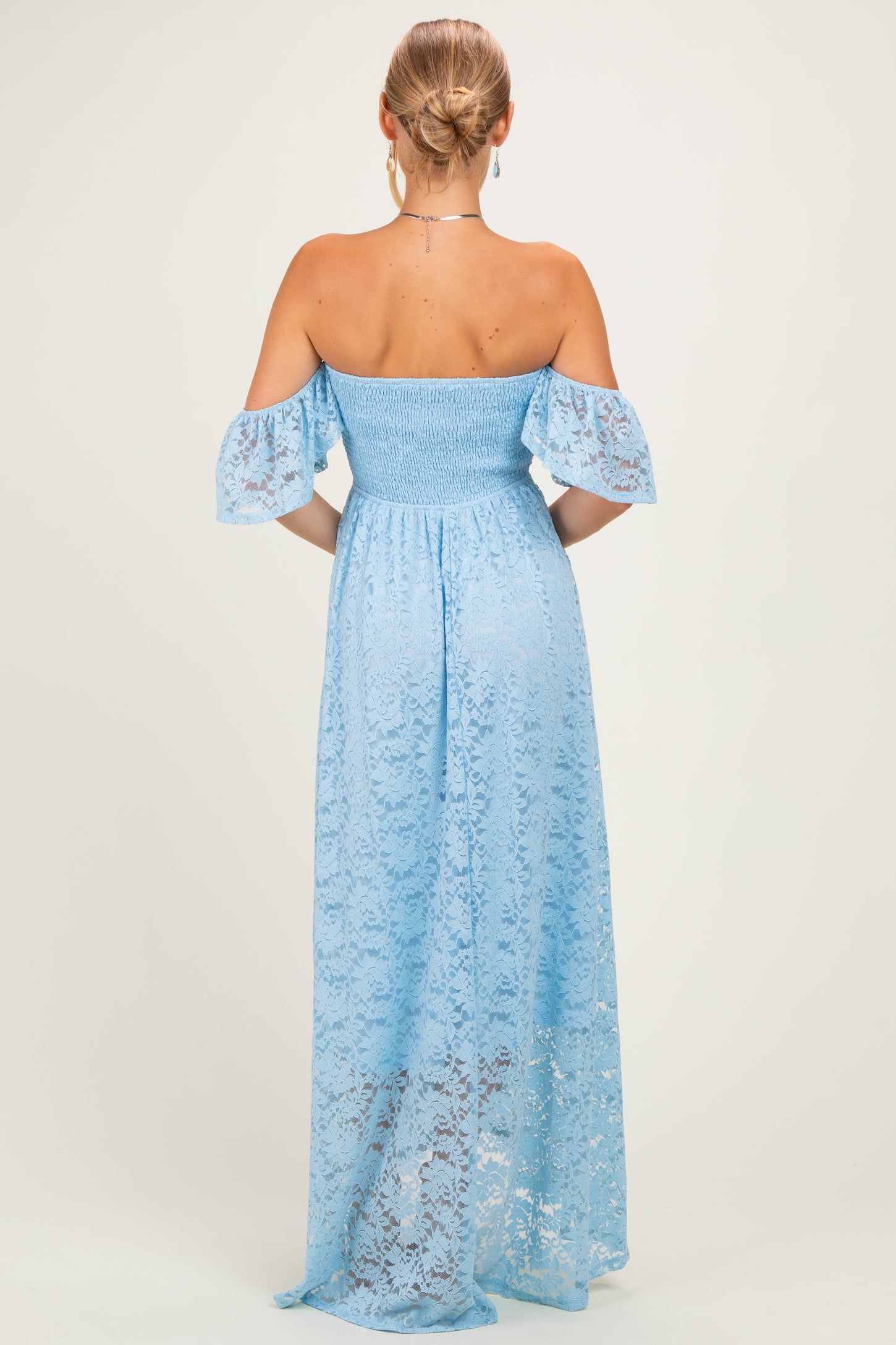 woman wearing a light blue off-the-shoulder lace maxi dress with smocked bodice and flutter sleeves