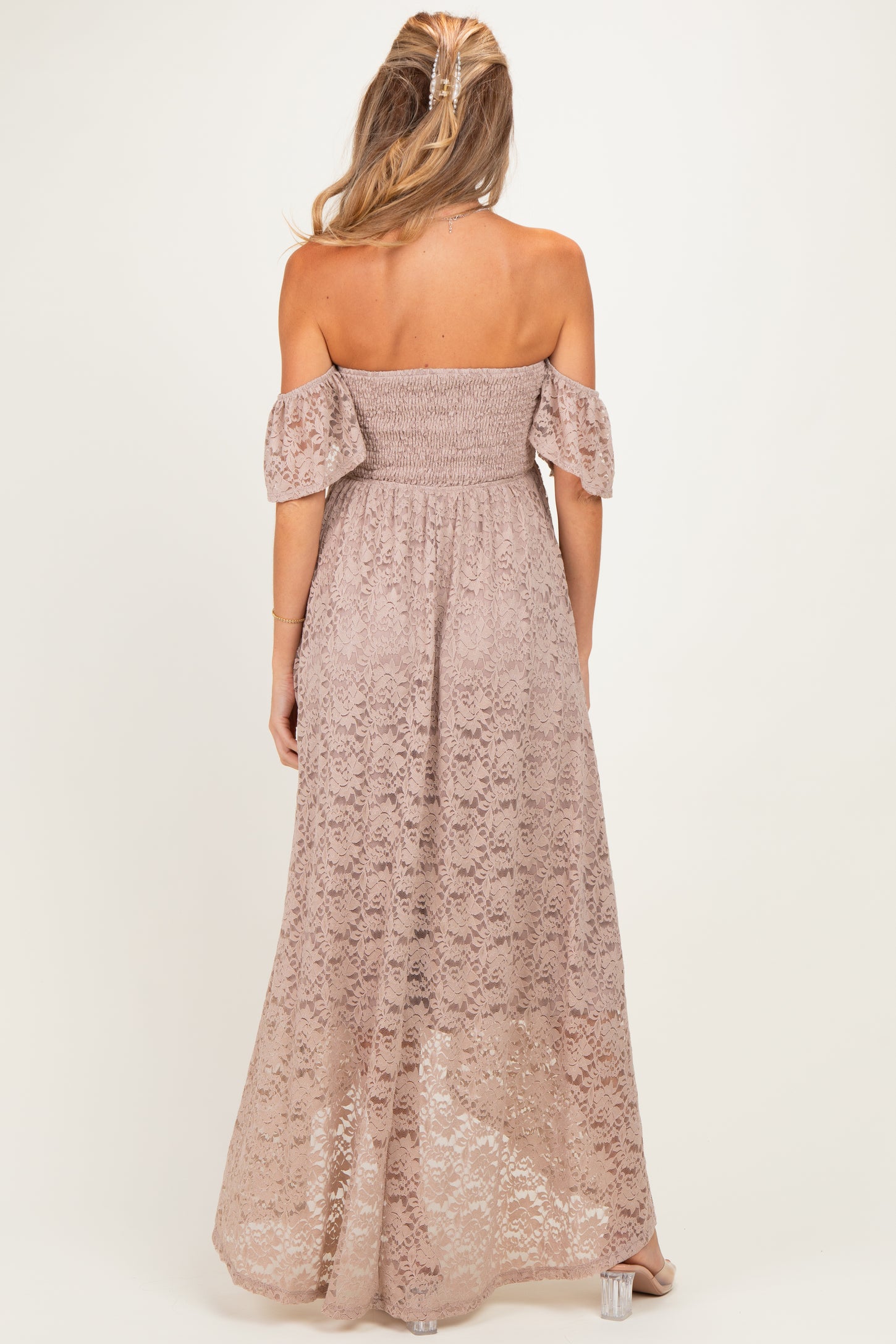 woman wearing a pink off-the-shoulder lace maternity maxi dress, showing a smocked bodice and flowy skirt from the back