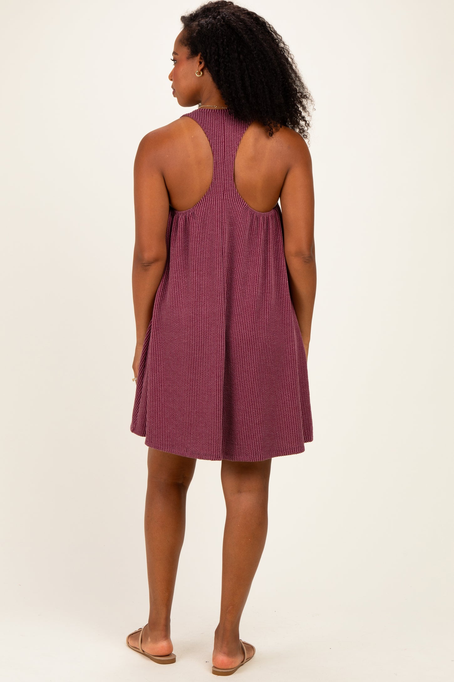 woman wearing a burgundy sleeveless backless dress with a loose fit and vertical stripes