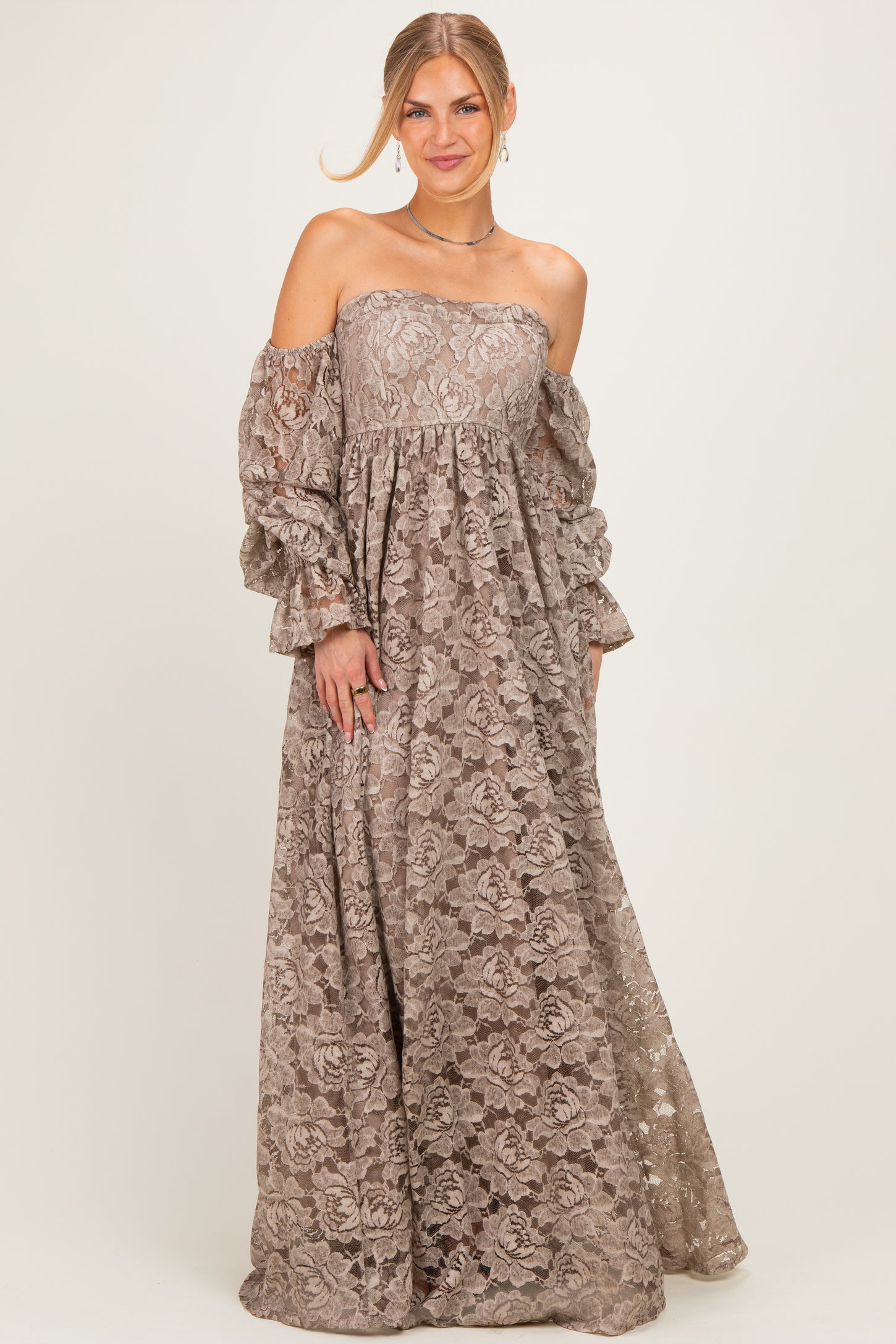 woman wearing a taupe off-the-shoulder lace maxi dress with long, puffed sleeves