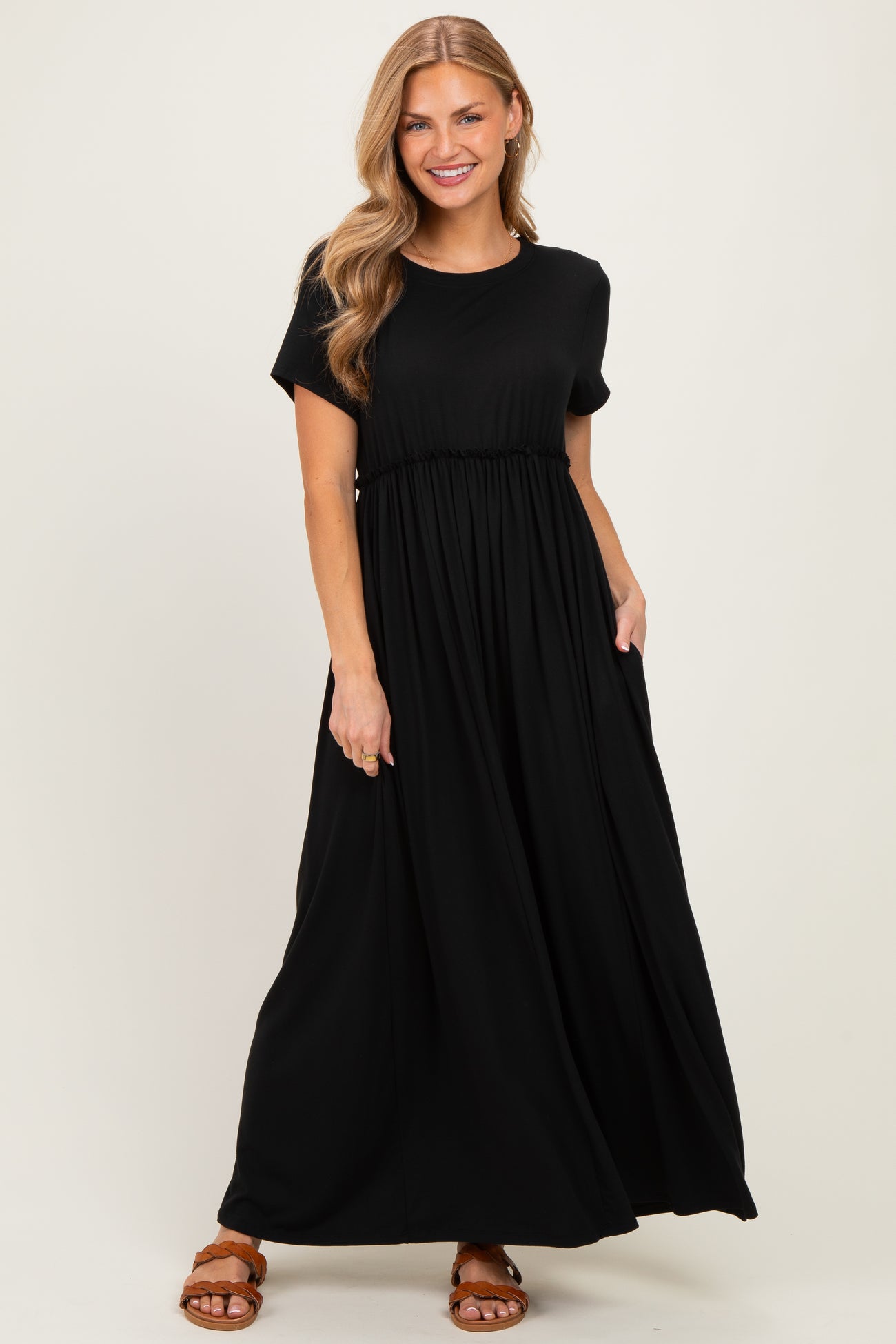 woman wearing a black short sleeve maxi dress with a gathered waist and side pockets