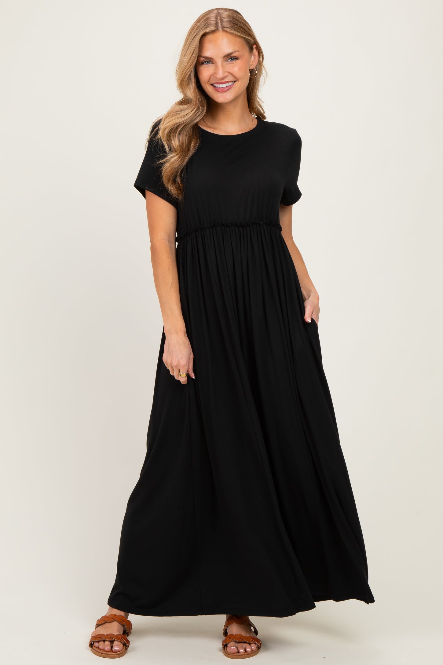 woman wearing a black short sleeve maxi dress with a gathered waist and side pockets