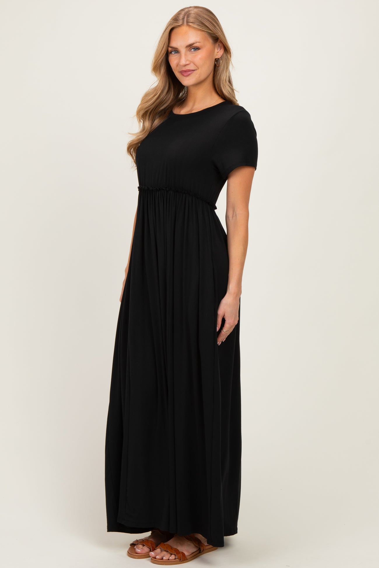 woman wearing a black short sleeve maxi dress with a gathered waist and flowing skirt