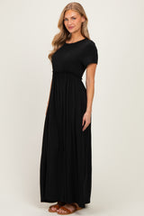 woman wearing a black short sleeve maxi dress with a gathered waist and flowing skirt