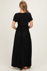 woman wearing a black maxi dress with a gathered waist and short sleeves, shown from the back