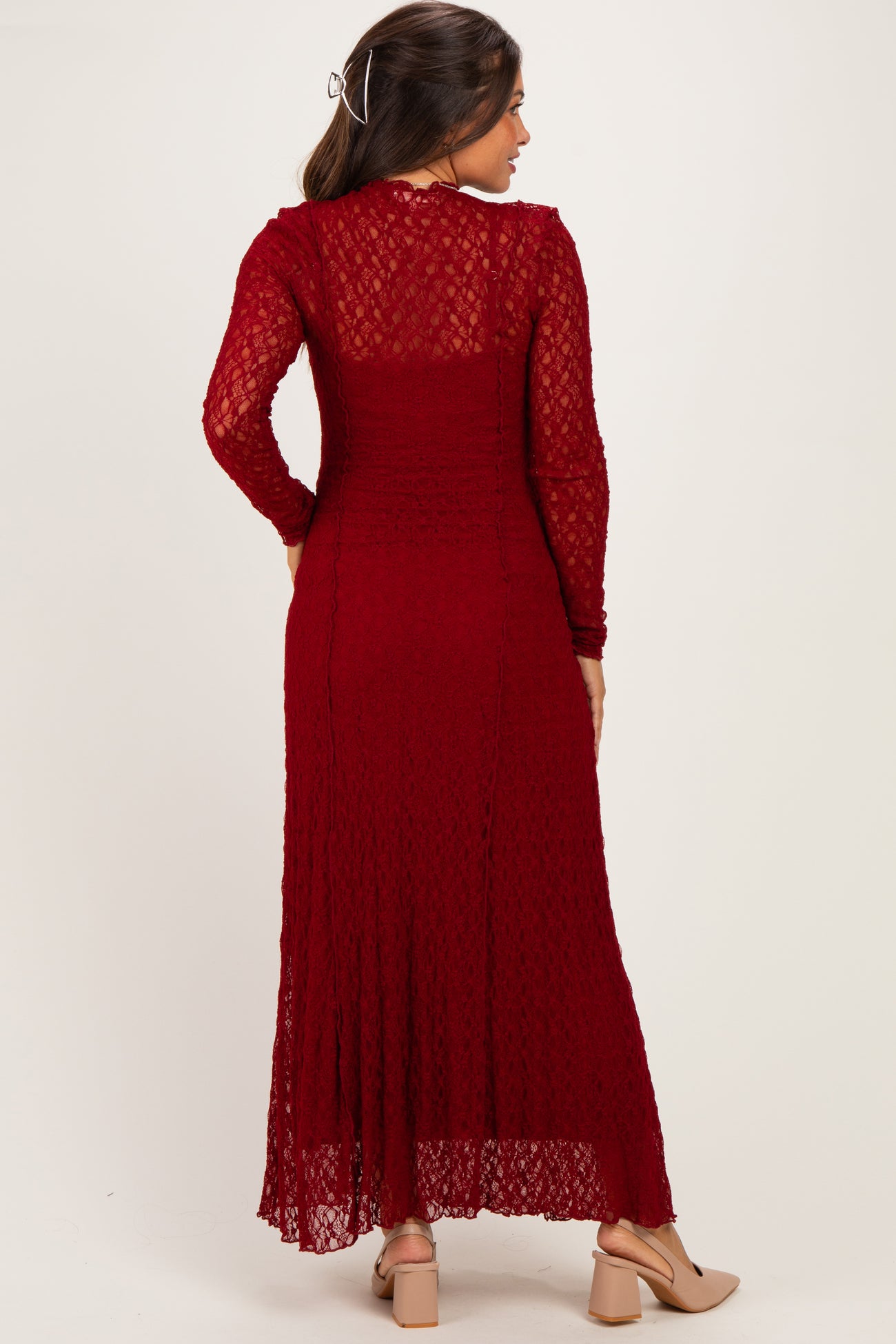 woman wearing a burgundy long sleeve maternity dress with lace detailing and a flowing skirt