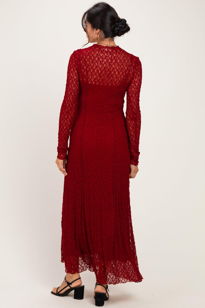 woman wearing a long sleeve burgundy lace maxi dress with a sheer back and flared hem, shown from the back