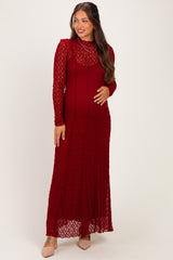 woman wearing a burgundy lace long sleeve maternity dress and showcasing her baby bump