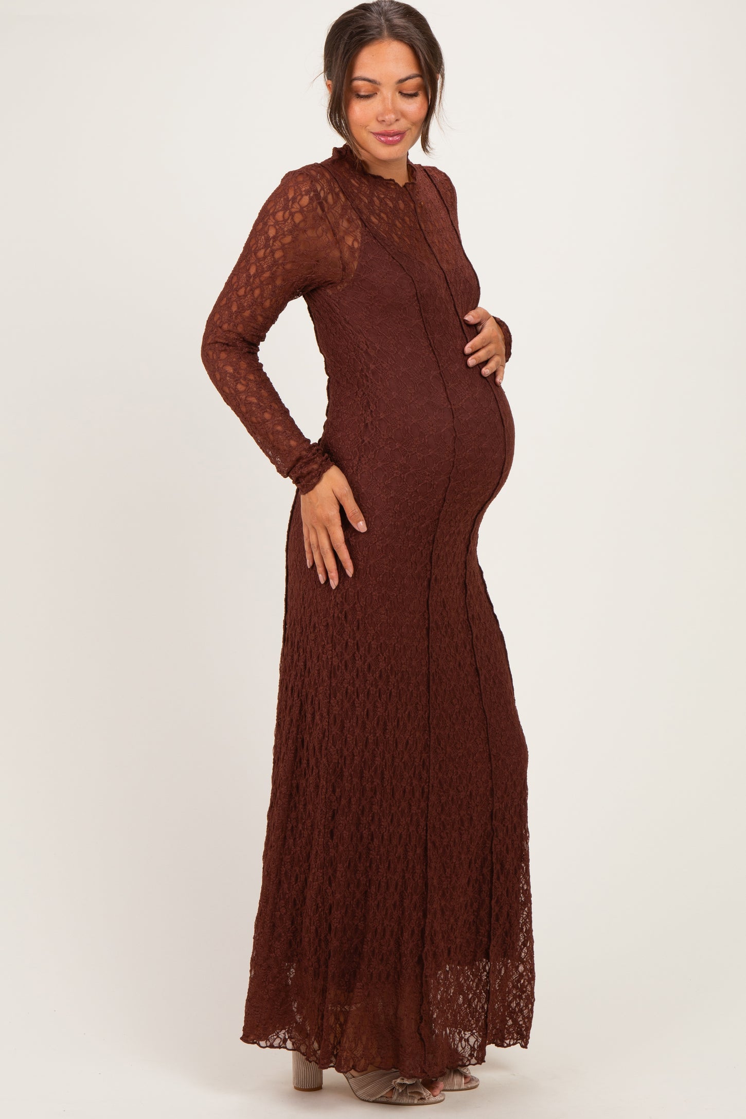 woman wearing a rust-colored long sleeve maternity maxi dress with a fitted bodice and flowy skirt, showing her baby bump
