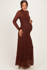 woman wearing a rust-colored long sleeve maternity maxi dress with a fitted bodice and flowy skirt, showing her baby bump