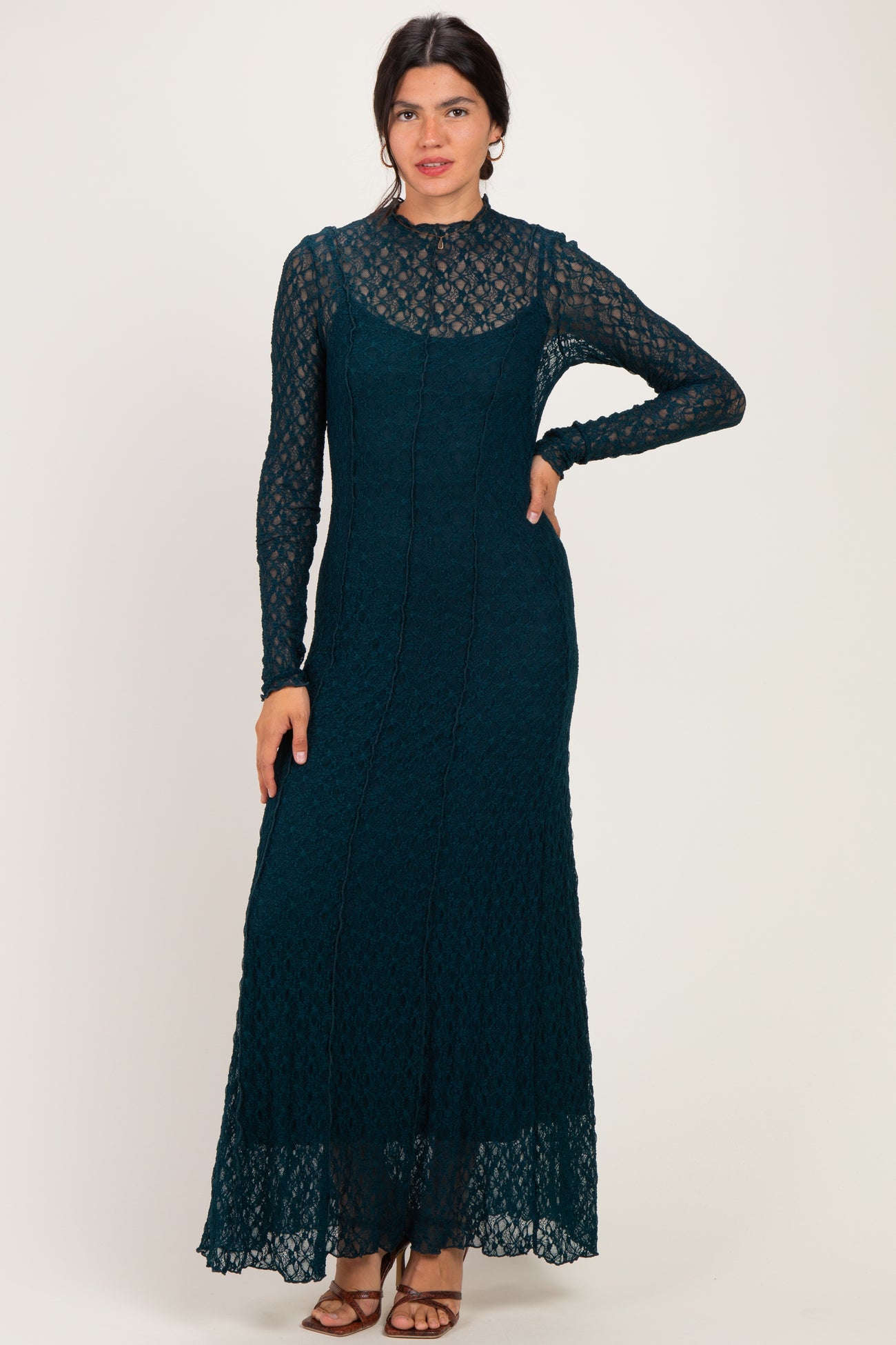 woman wearing a teal long sleeve lace maxi dress with a fitted silhouette and a flared hem