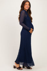 woman wearing a navy blue lace maternity dress with long sleeves and a baby bump visible