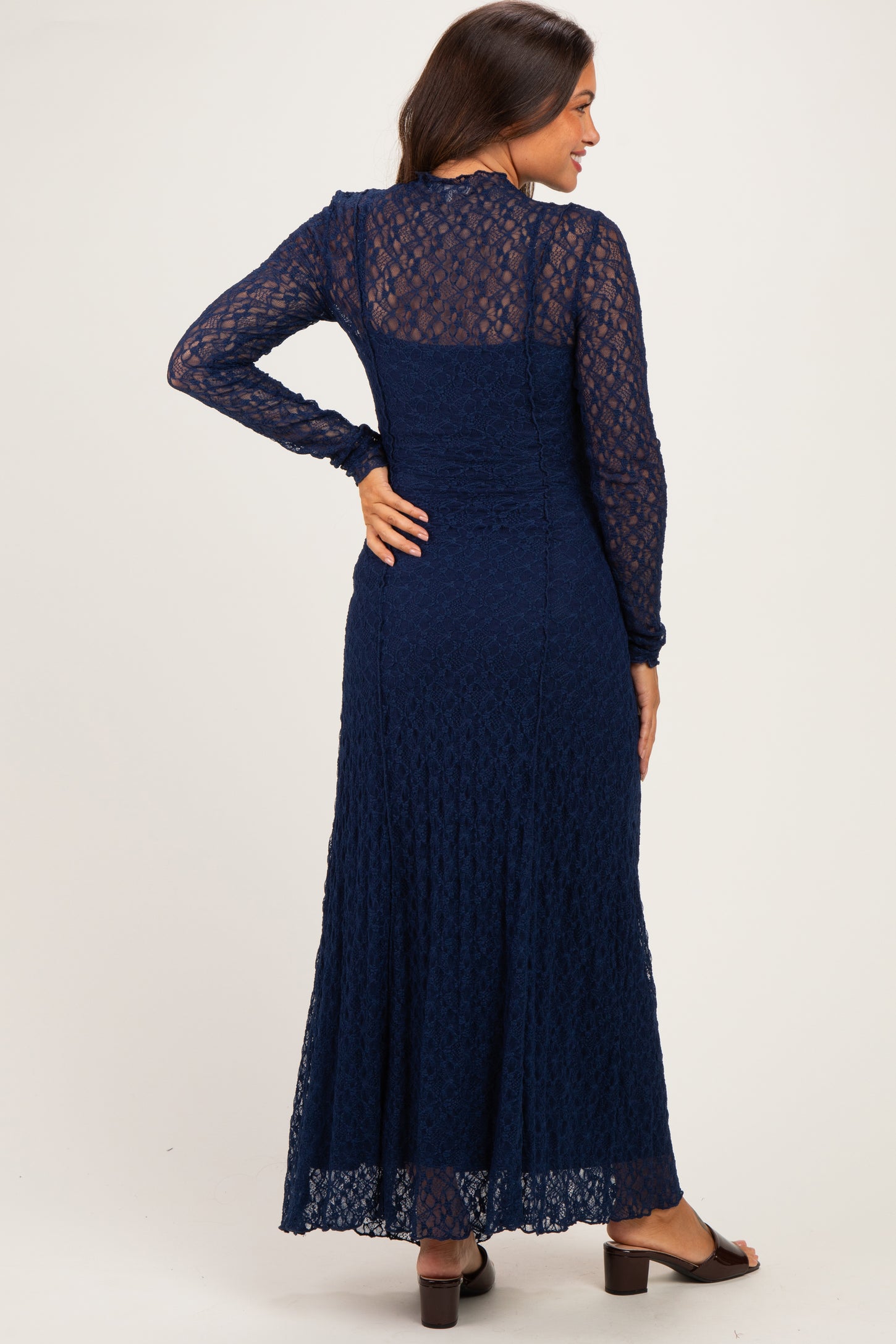 woman wearing a navy blue lace maternity maxi dress with long sleeves and a flowing skirt, showing a baby bump
