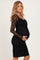 woman wearing a black lace long sleeve maternity dress and showing her baby bump